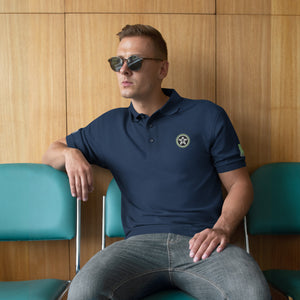 A man sitting in a chair wearing sunglasses and a Boss Uncaged Store polo shirt.