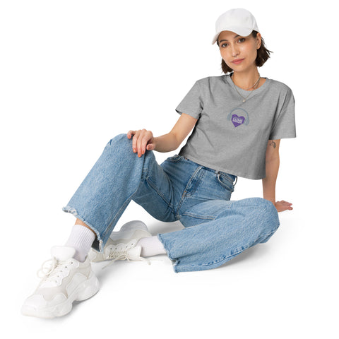 A woman wearing jeans and a t-shirt, with an Affirmation I Love Podcasts - Women’s crop top from the Boss Uncaged Store, sitting on the ground while listening to the Boss Uncaged podcast.