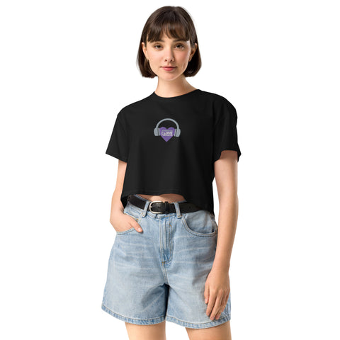 A woman wearing a black cropped t-shirt with a purple heart on it, confidently representing Boss Uncaged Store through her stylish choice of apparel, the Affirmation I Love Podcasts - Women’s crop top.