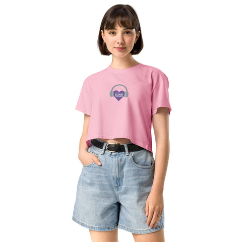 A woman wearing the Affirmation I Love Podcasts - Women's crop top from Boss Uncaged Store, showcasing her love for podcasts with a pink cropped t-shirt featuring a purple heart on it.