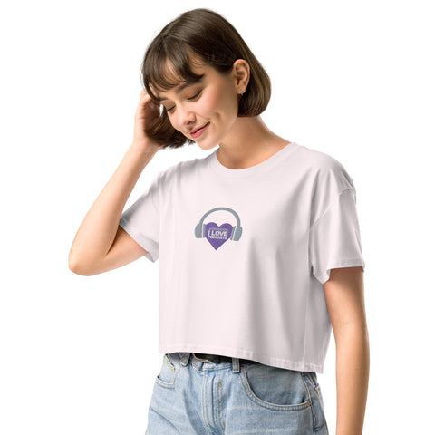 A trendy woman wearing a Boss Uncaged Store Affirmation I Love Podcasts women's crop top with a purple heart on it.