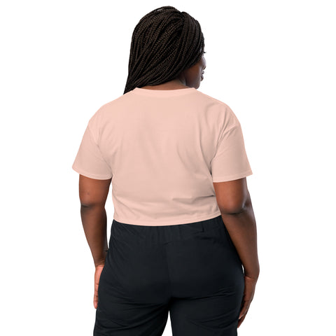The back view of a woman wearing a pink crop top with the brand name "Affirmation I Love Podcasts - Women’s crop top" from the Boss Uncaged Store and black pants while listening to the Boss Uncaged podcast for affirmation.