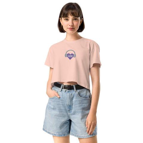 A woman wearing a pink cropped t-shirt with a purple heart on it, radiating confidence and representing the Boss Uncaged movement, is wearing the Affirmation I Love Podcasts - Women’s crop top from the Boss Uncaged Store.
