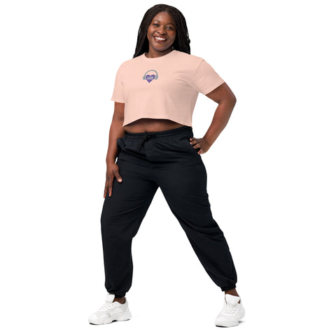 A woman wearing a pink Affirmation I Love Podcasts - Women's crop top from Boss Uncaged Store and black joggers, exuding confidence and empowerment.