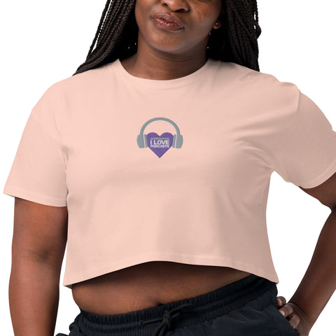 A woman wearing a pink Affirmation I Love Podcasts - Women’s crop top with the Boss Uncaged Store logo on it, listening to Boss Uncaged podcasts.