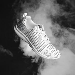 A black and white photo of a Boss Uncaged Workflow Athletic Shoes (White) sneaker in the air from Boss Uncaged Store.