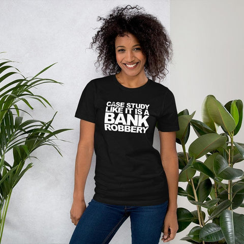 Image of A person stands indoors next to plants, wearing a black t-shirt from Buteke that reads "CASE THE STUDY LIKE IT IS A BANK ROBBERY! GIMME THE LOOT!" in white text. This scene illustrates how impactful case studies can transform customer perception and bring your products to life.