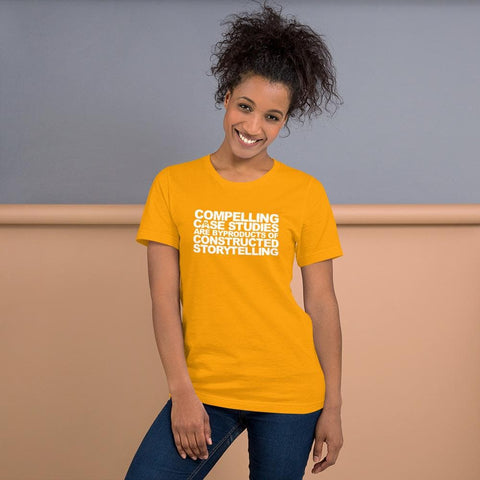 Image of A person with curly hair in a ponytail poses and smiles, wearing a yellow t-shirt from Buteke with text reading "COMPELLING CASE STUDIES ARE BYPRODUCTS OF CONSTRUCTED STORYTELLING.”