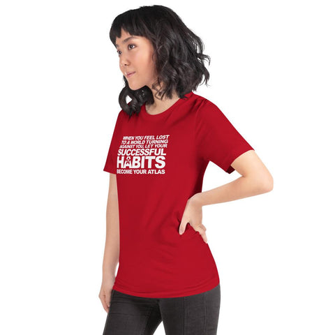 Image of A woman wearing a red t-shirt with the words, "WHEN YOU FEEL LOST TO A WORLD TURNING AGAINST YOU, LET YOUR SUCCESSFUL HABITS BECOME YOUR ATLAS." by Boss Uncaged Store.