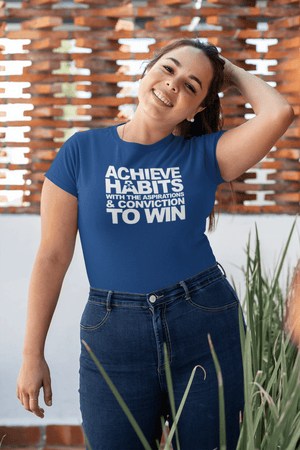 A woman wearing a blue t - shirt that says "ACHIEVE HABITS WITH THE ASPIRATIONS AND CONVICTION TO WIN." from Boss Uncaged Store.
