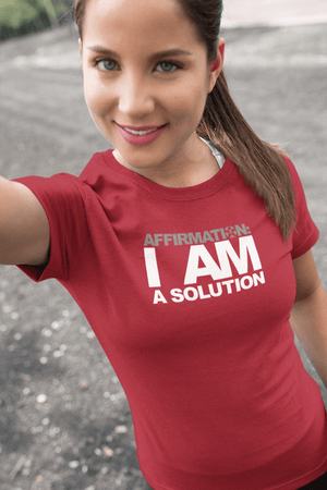 A woman wearing a red t-shirt that says "AFFIRMATION: 'I AM A SOLUTION'" from Boss Uncaged Store.