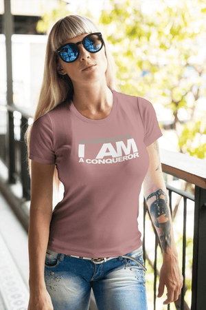 A woman wearing a pink t-shirt with the words "AFFIRMATION: 'I AM A CONQUEROR'" from Boss Uncaged Store.