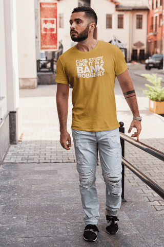 Image of Man walking on a city street wearing a yellow Buteke t-shirt that reads "CASE THE STUDY LIKE IT IS A BANK ROBBERY! GIMME THE LOOT!" and light blue ripped jeans, effortlessly bringing your products to life.